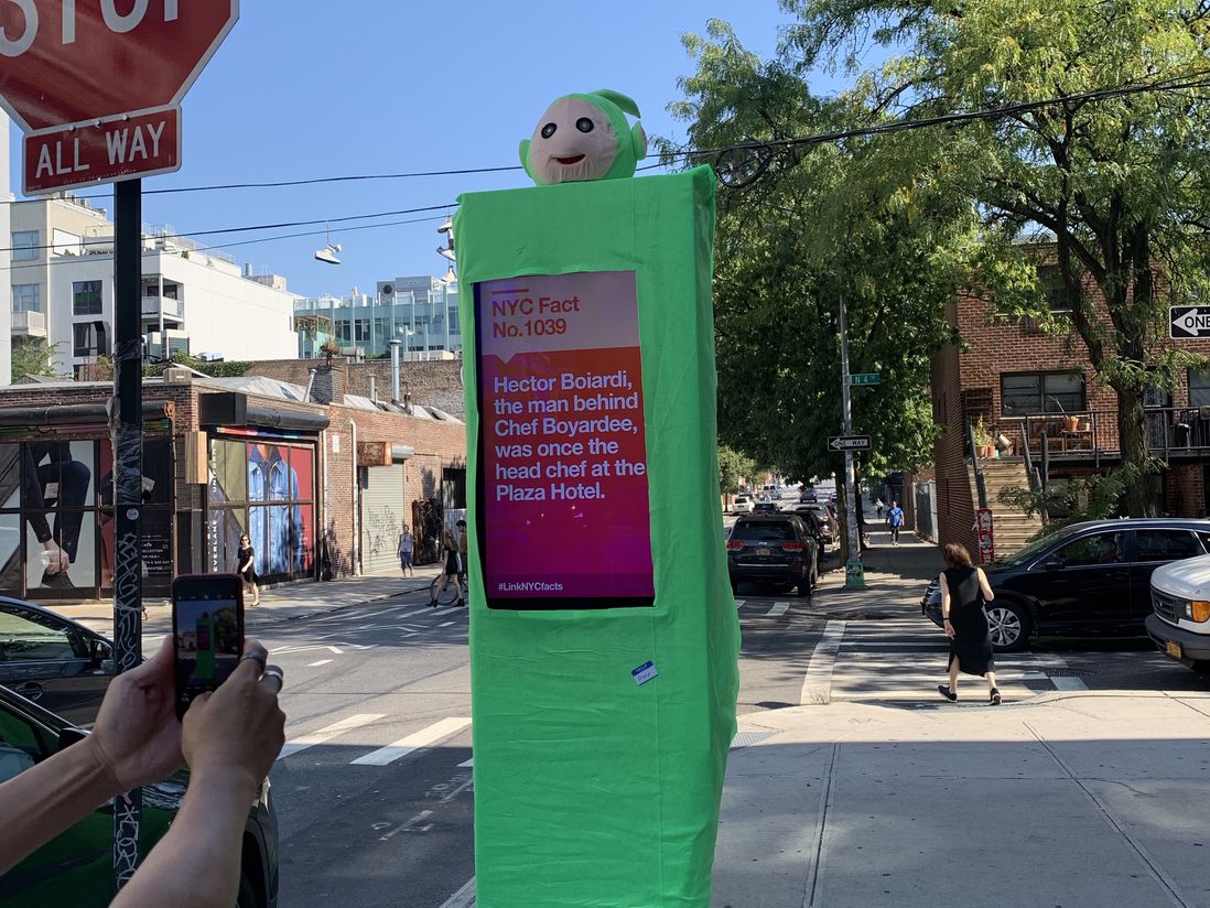 This is a photo of a LinkNYC kiosk in a Teletubby suit.